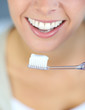 Closeup on woman's toothy smile brushing her teeth