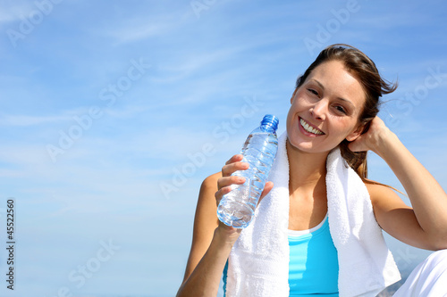 Photo: Thirsty fitness girl holding bottle of water Thirsty fitness girl holding bottle of water