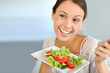 Closeup of cheerful woman eating fresh salad
