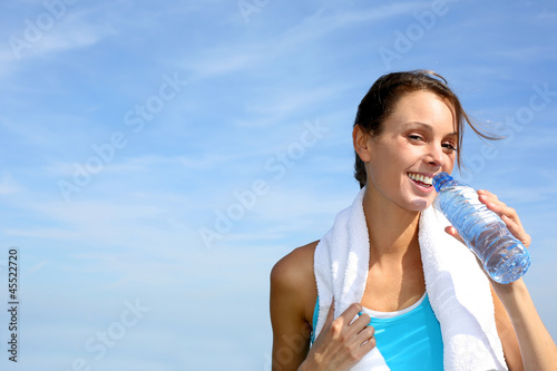 Photo: Thirsty fitness girl holding bottle of water Thirsty fitness girl holding bottle of water