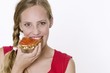 Young woman eating a slice of bread with strawberry and rhubarb jam