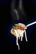 Linguine with a minced meat sauce, tomatoes and basil on a fork