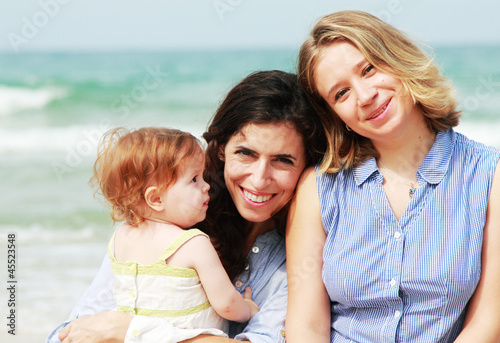 Photo: two beautiful girls with a baby on the beach two beautiful girls with a baby on the beach