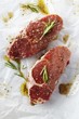 Photo: Two Raw Steaks with Marinade and Rosemary on Butcher's Paper Two Raw Steaks with Marinade and Rosemary on Butcher's Paper