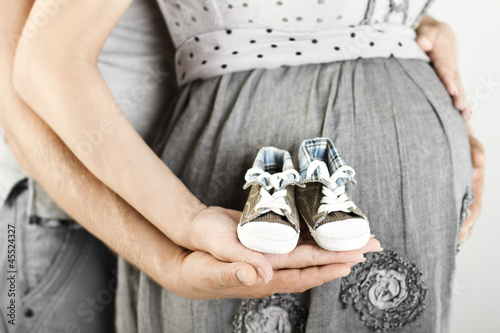 Photo: Newborn baby booties in parents hands. Close up. Newborn baby booties in parents hands. Close up.