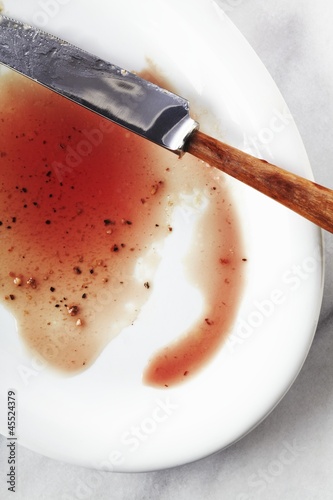 Photo: Juices from a Cooked Steak on a White Plate; Knife Juices from a Cooked Steak on a White Plate; Knife