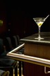 A martini with an olive on a bar