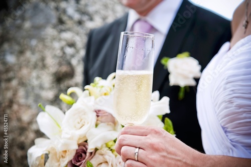 Photo: A bride and groom with a glass of champagne and a bouquet A bride and groom with a glass of champagne and a bouquet