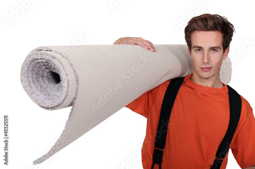 Photo: Man carrying a roll of carpet Man carrying a roll of carpet