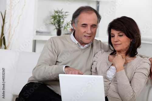 Photo: Mature couple on a sofa with laptop computer Mature couple on a sofa with laptop computer