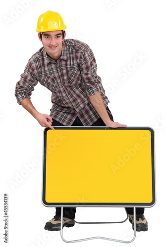 Photo: A road worker pointing at a blank sign. A road worker pointing at a blank sign.
