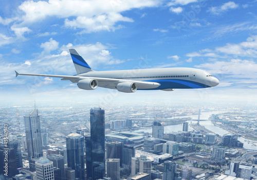 Photo: White passenger plane flying above a city White passenger plane flying above a city