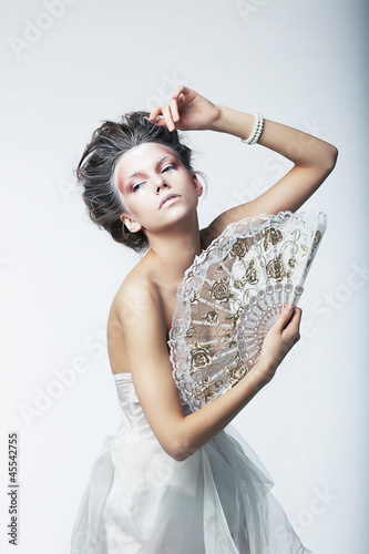Photo: Enigma. Fantasy. Retro fashion woman with white vintage fan Enigma. Fantasy. Retro fashion woman with white vintage fan