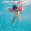 Underwater little kid in swimming pool with musk and armrests.