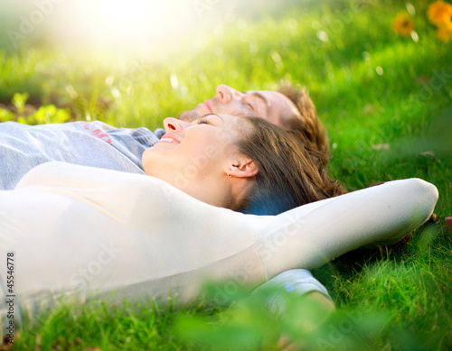Photo: Young Couple Lying on Grass Outdoor Young Couple Lying on Grass Outdoor