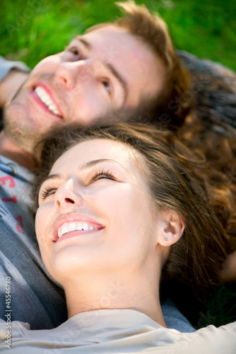 Photo: Young Couple Lying on Grass Outdoor Young Couple Lying on Grass Outdoor