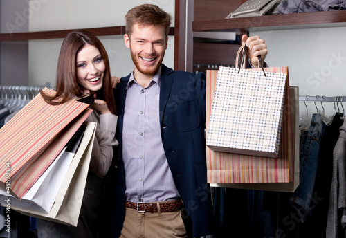 Photo: Cheerful couple show their purchases after shopping Cheerful couple show their purchases after shopping