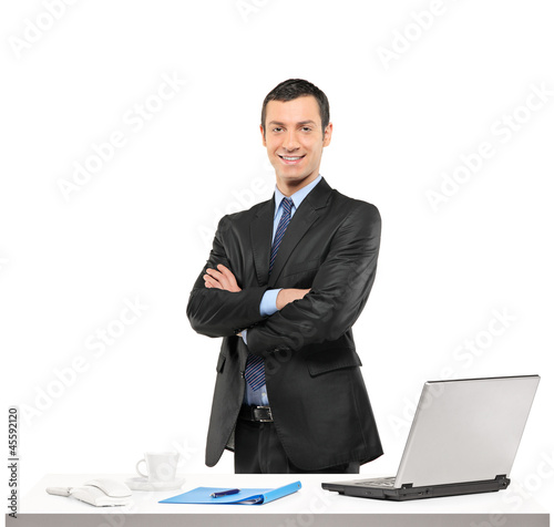 Photo: A confident businessman posing at his workplace A confident businessman posing at his workplace