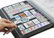 Photo: Hand holding postage stamp with tweezers over album Hand holding postage stamp with tweezers over album