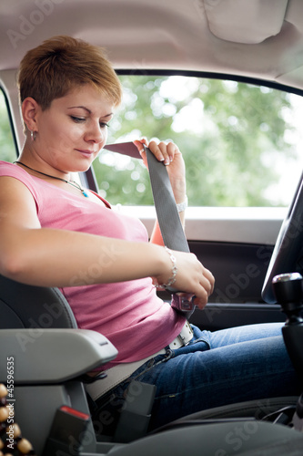 Photo: Woman putting seat belt Woman putting seat belt