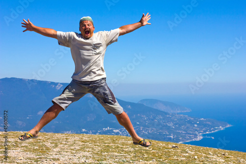 Photo: happy man jumping on a background of mountains and sky and sea happy man jumping on a background of mountains and sky and sea