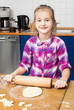 Photo: Little girl kneading dough with rolling pin on table Little girl kneading dough with rolling pin on table