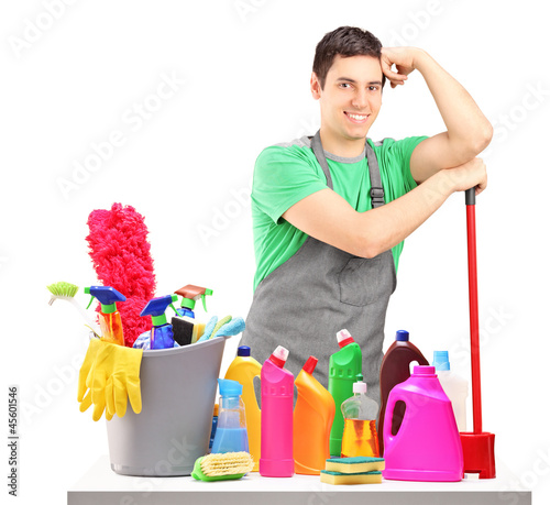 Photo: Young male cleaner with cleaning equipment isolated on white Young male cleaner with cleaning equipment isolated on white