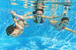 Happy family underwater in swimming pool, summer vacation