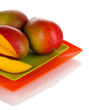 Ripe appetizing mango on red plate isolated on white