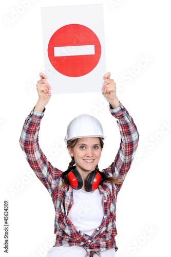 Photo: Female manual worker holding warning sign Female manual worker holding warning sign