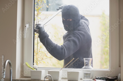 Photo: Burglar breaking a kitchen window Burglar breaking a kitchen window
