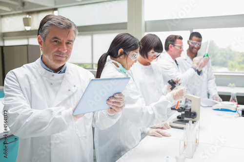 Photo: Smiling chemist using tablet pc Smiling chemist using tablet pc