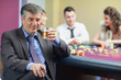 Man drinking whiskey at roulette table