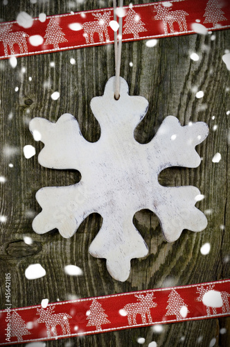 Photo: Schneeflocke aus Holz mit Schleifeband und Schnee Schneeflocke aus Holz mit Schleifeband und Schnee