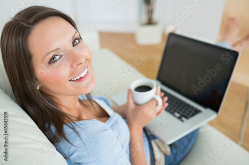 Photo: Woman drinking a coffee and using her laptop Woman drinking a coffee and using her laptop