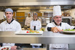 Smiling chef putting salad on order station
