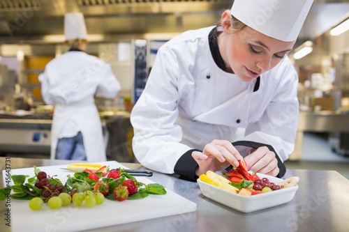 Photo: Chef putting a strawberry in the fruit salad Chef putting a strawberry in the fruit salad