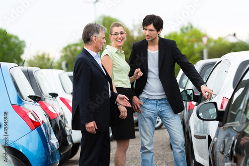 Photo: Couple looking at car on yard of dealer Couple looking at car on yard of dealer