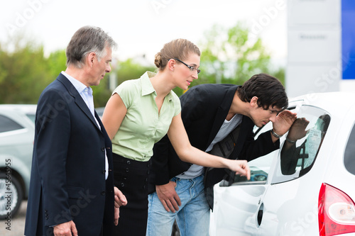 Photo: Couple looking at car on yard of dealer Couple looking at car on yard of dealer