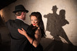 Two tango dancers performing under spotlight indoors