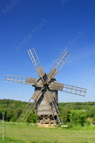 Photo: Old wind mill on a spring meadow with blue sky Old wind mill on a spring meadow with blue sky