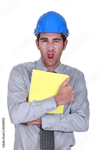 Photo: Man yawning whilst clutching paperwork Man yawning whilst clutching paperwork