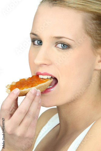 Photo: Woman eating a piece of bread with jam Woman eating a piece of bread with jam