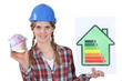 female heating engineer holding money box in shape of house