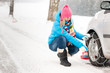 Woman putting winter tire chains car wheel