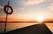 Safety equipment. Lifebuoy on the pier in the orange sunrise