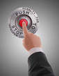 Red STOP button pressed by businessman's finger