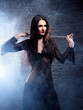 A young brunette in a black dress holding a metal chain