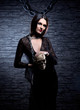 A young brunette in a dark dress holding a human skull