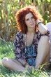 Portrait - Frau mit roten Locken in einer Wiese sitzend